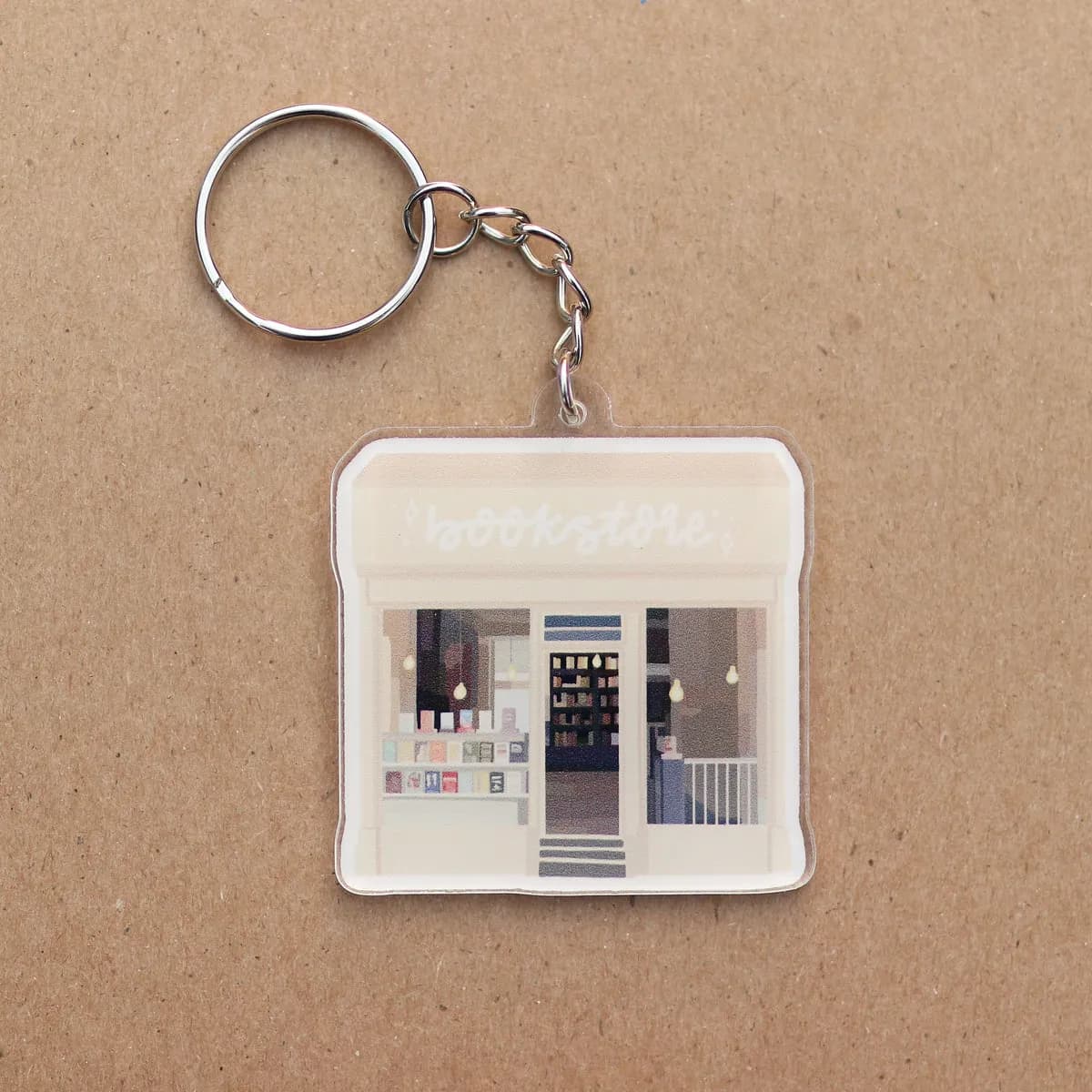 Bookstore acrylic keychain laid flat, storefront illustration visible