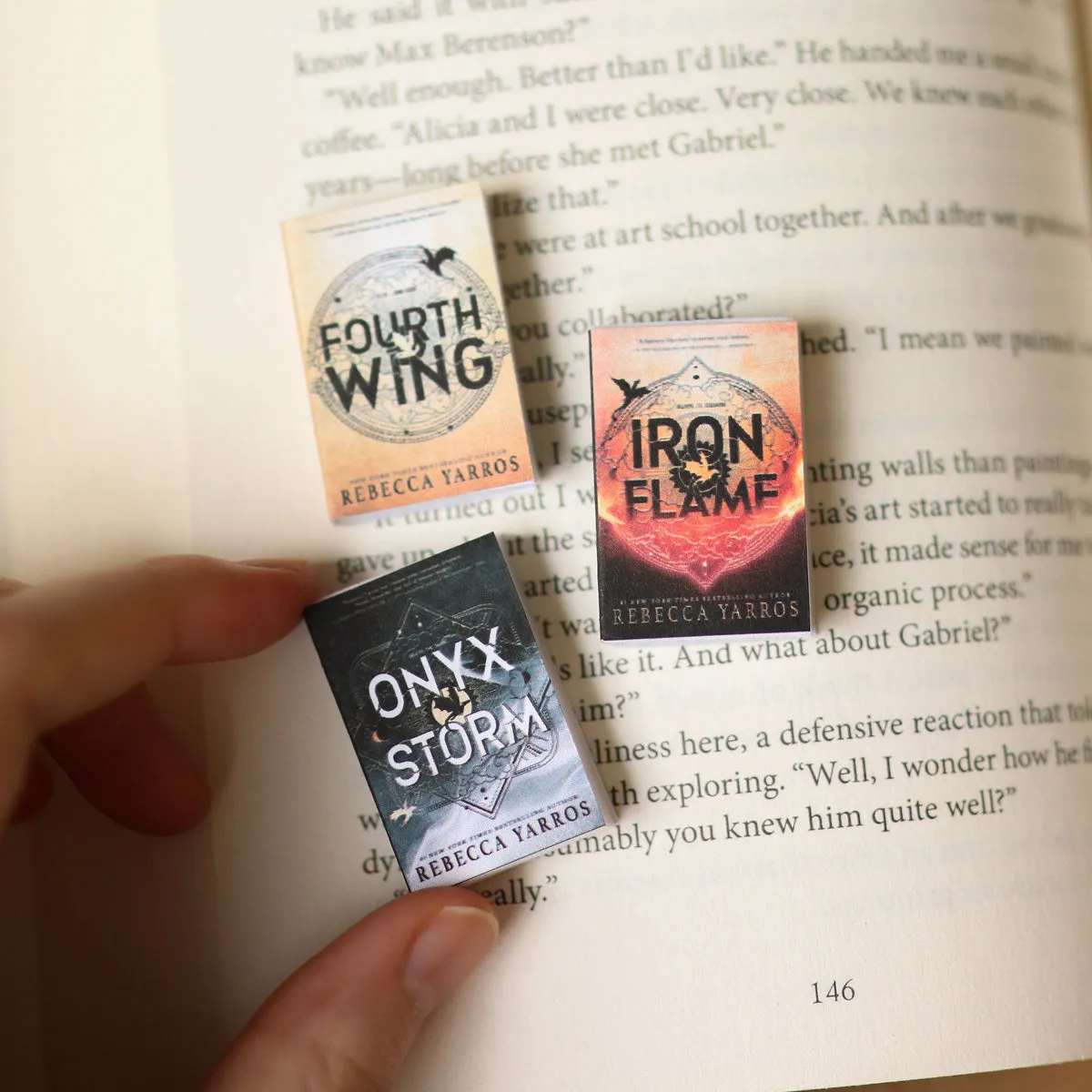 Mini Fourth Wing, Iron Flame and Onyx Storm covers laid on an open book