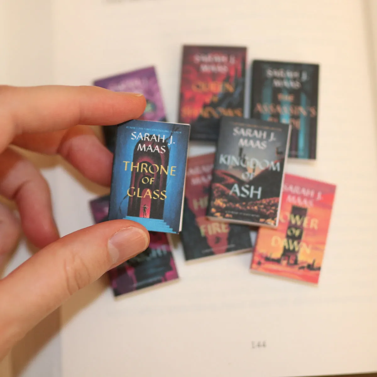 Six mini Sarah J. Maas covers fanned across a hand